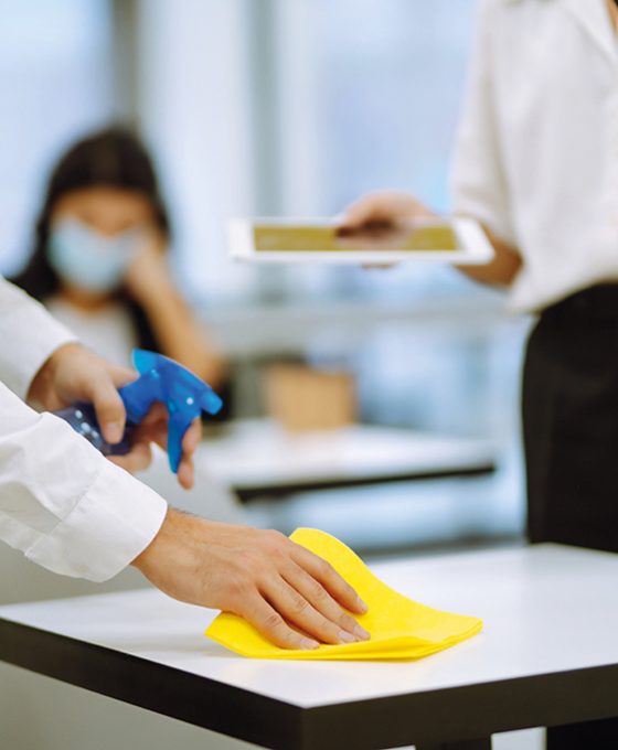 Cleaning and disinfection of the desktop. Man in protective sterile mask cleans the working desk.