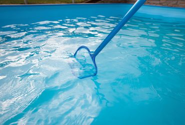 Young man hands cleaning pool by net of the dust, maintenance